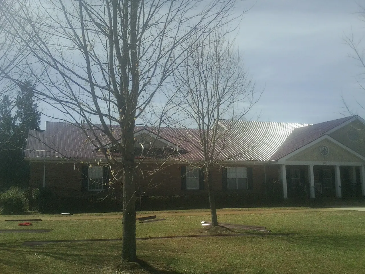 Red metal roof on a brick building seen from the front lawn in Albany